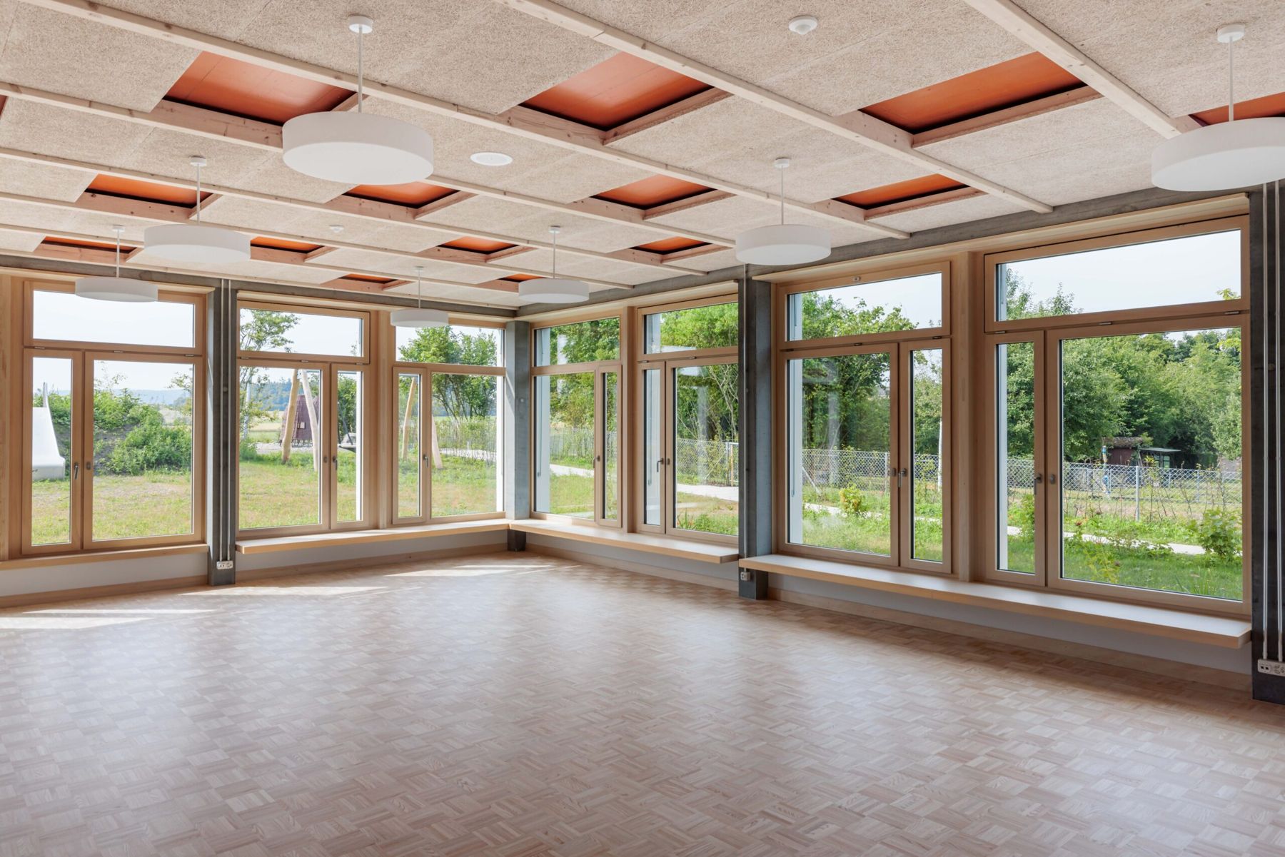 Grosser Raum mit Holzbalkenlage und Fensterfront